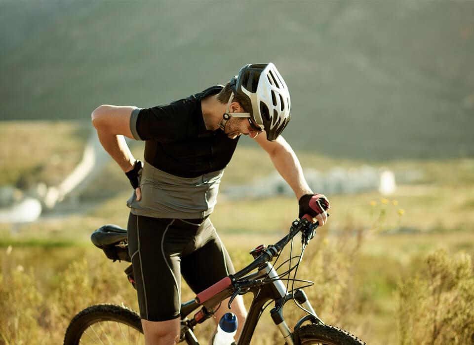 Image of a bicycle rider holding her back and feeling pain